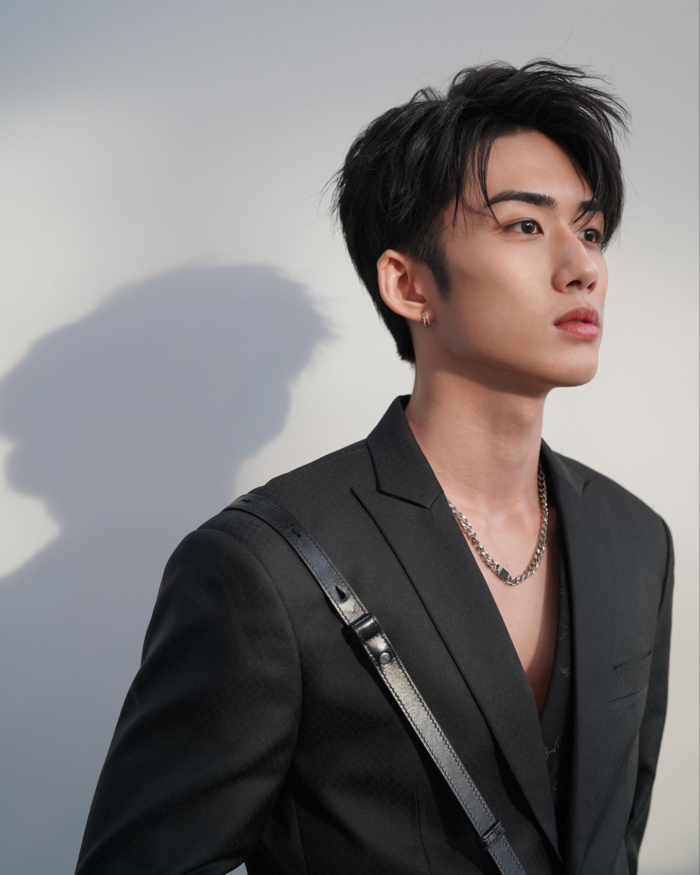 YANG YAN in a black suit against a pale backdrop