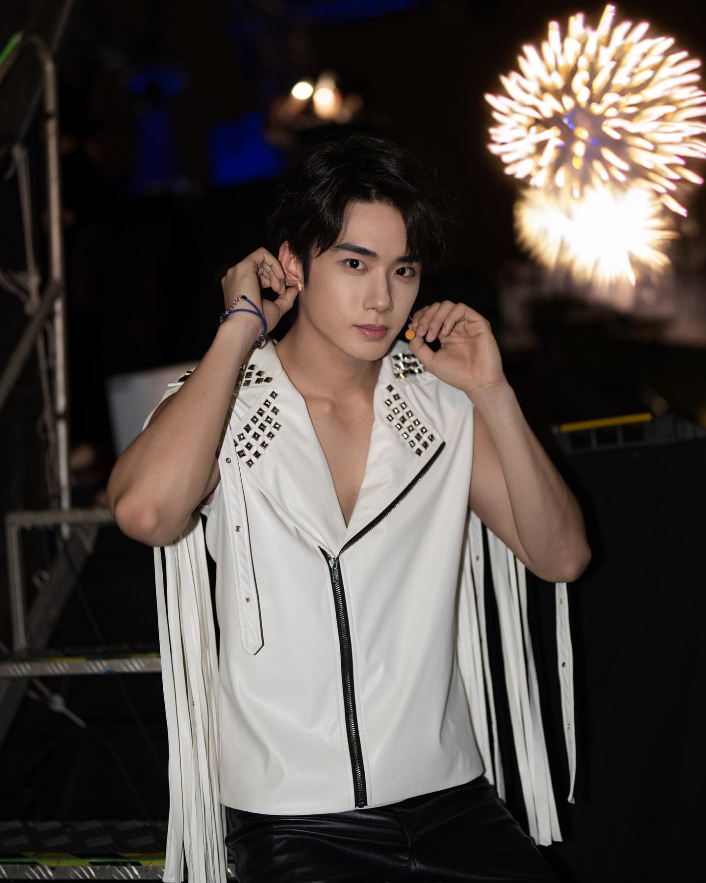 YANG YAN adjusting his earpieces near a stage