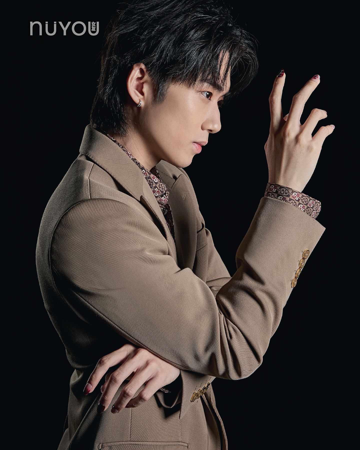 YANG YAN in a brown suit against a dark backdrop