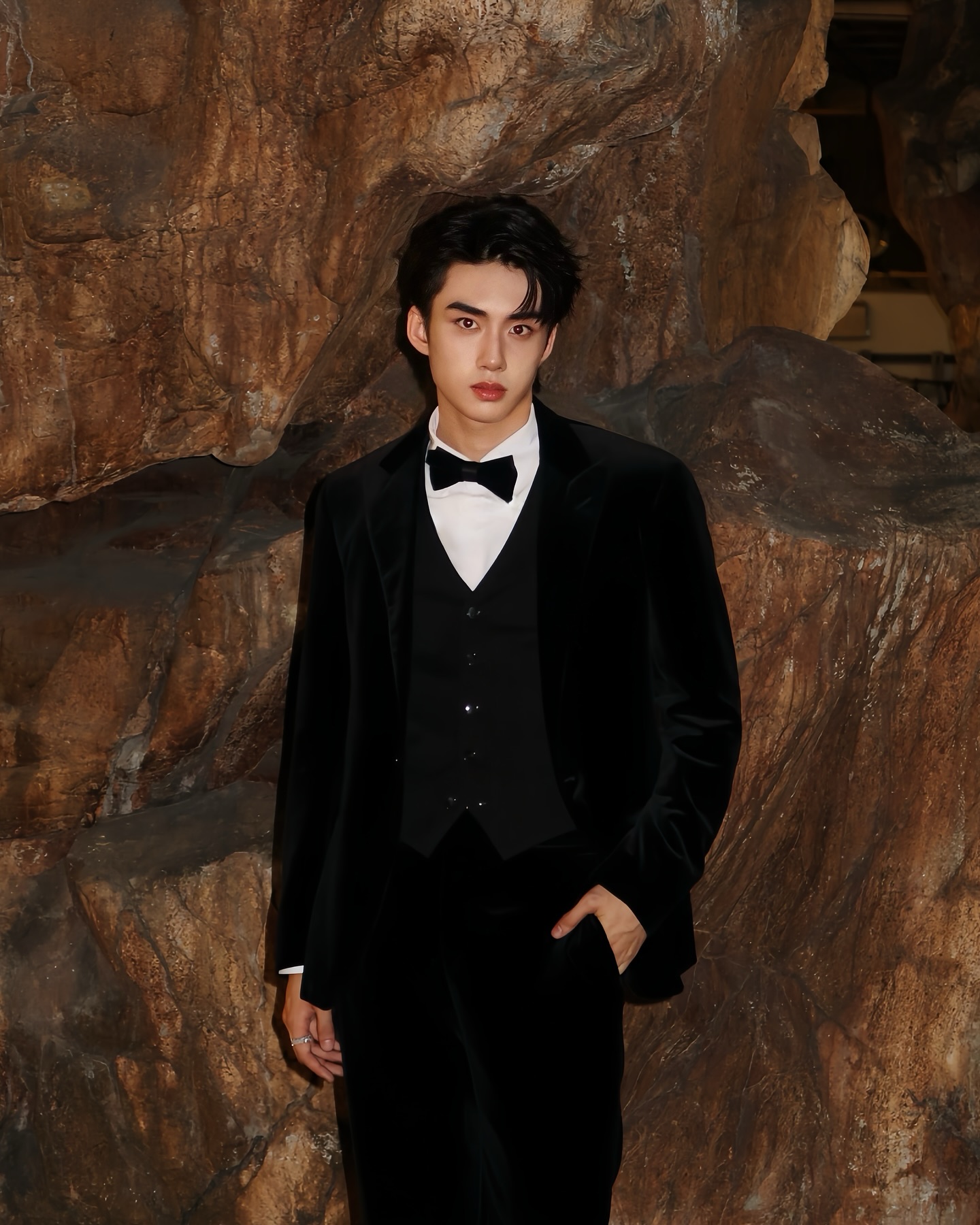 YANG YAN in a black tuxedo against a stone wall