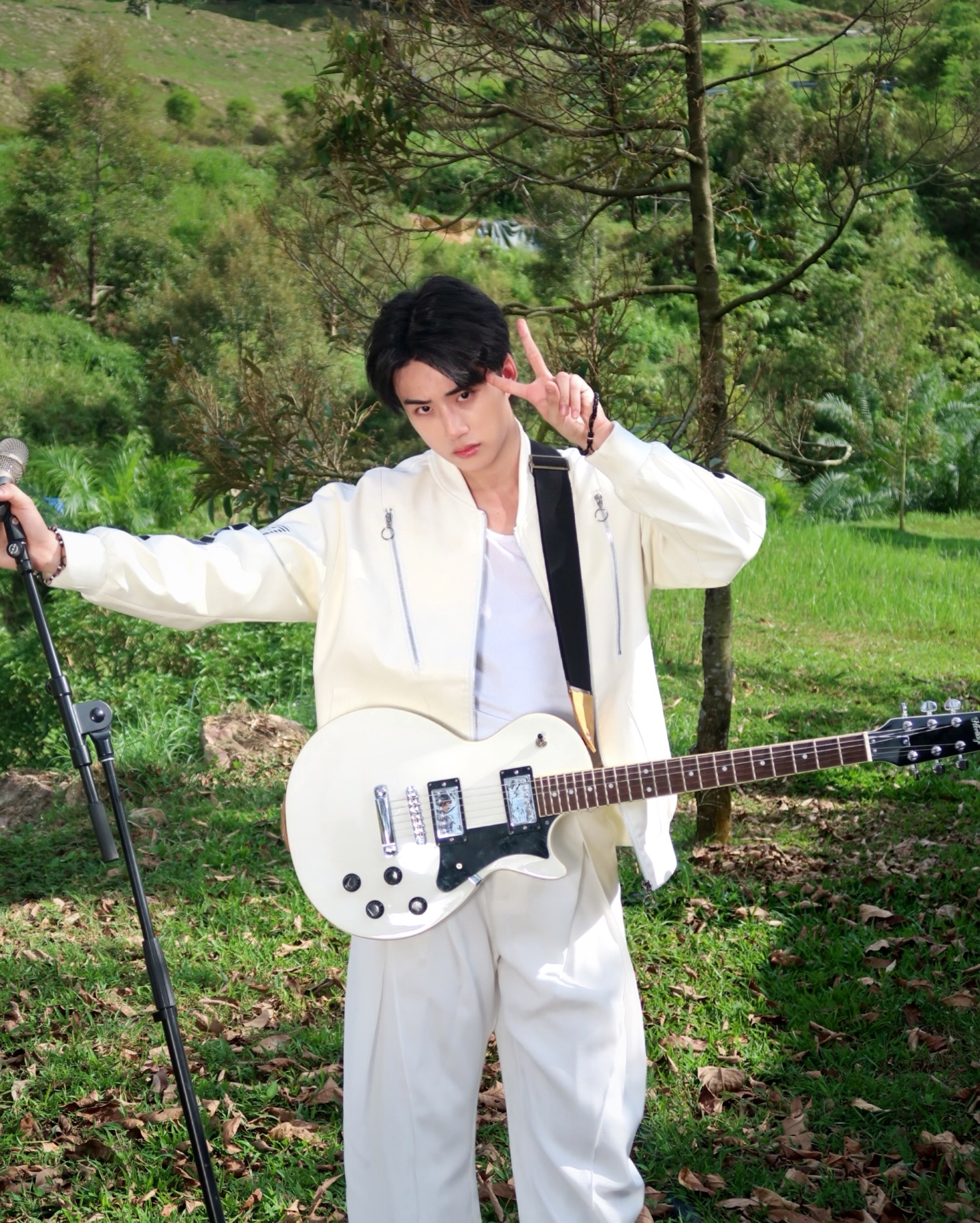YANG YAN outdoors in white holding a white electric guitar