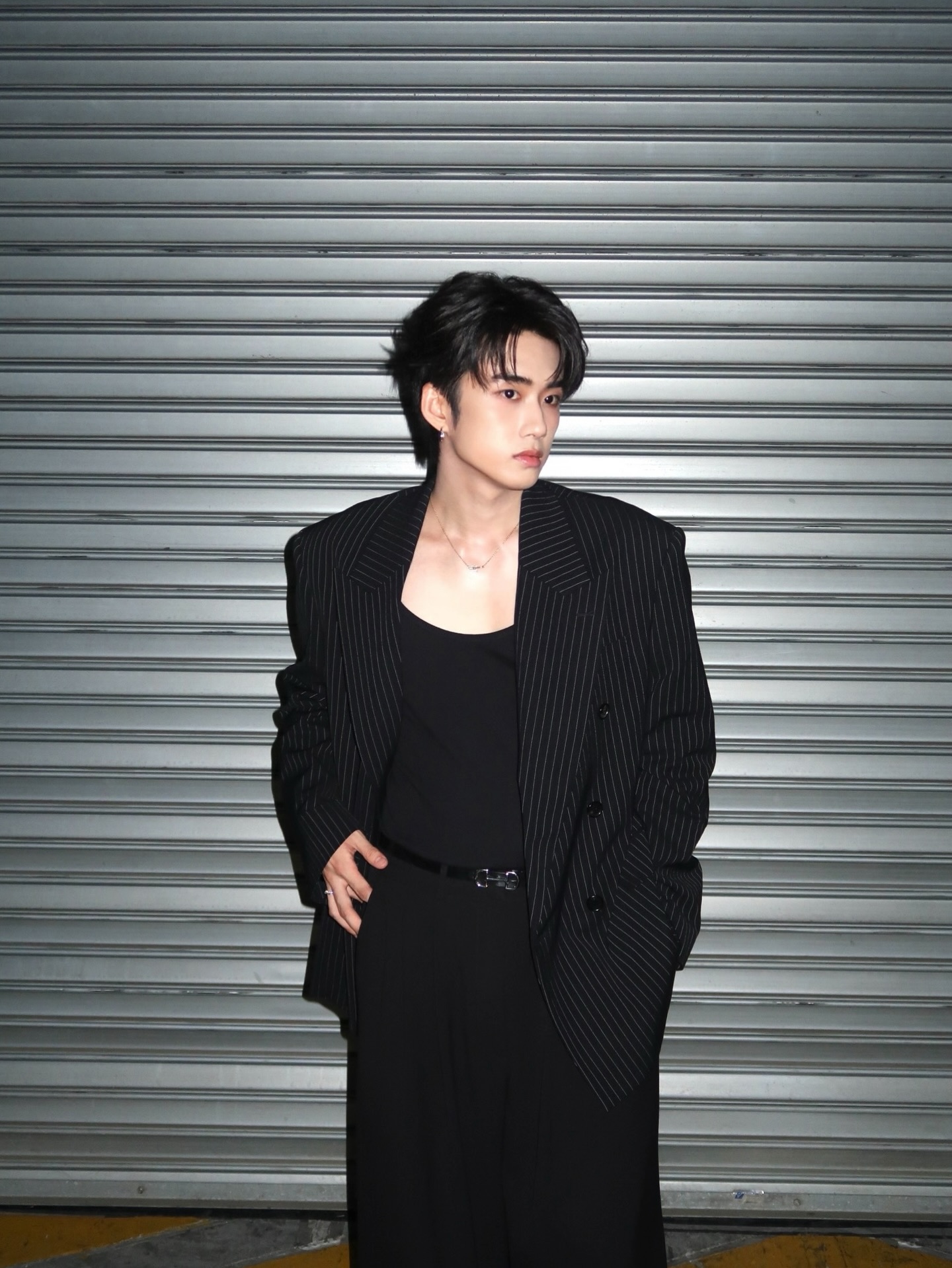 YANG YAN in an oversized pinstripe blazer against a metal shutter at night