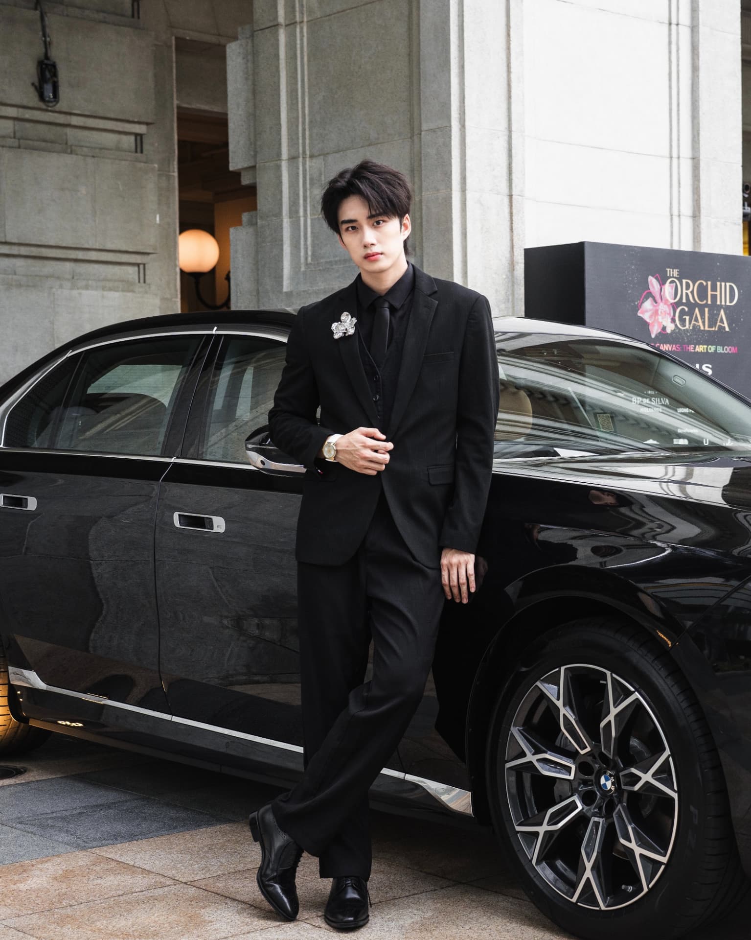 YANG YAN in a black suit with a floral brooch beside a black car at a gala