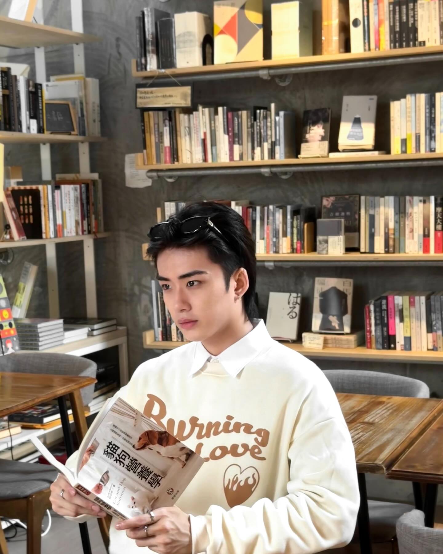 YANG YAN in a cream sweatshirt reading in a bookstore