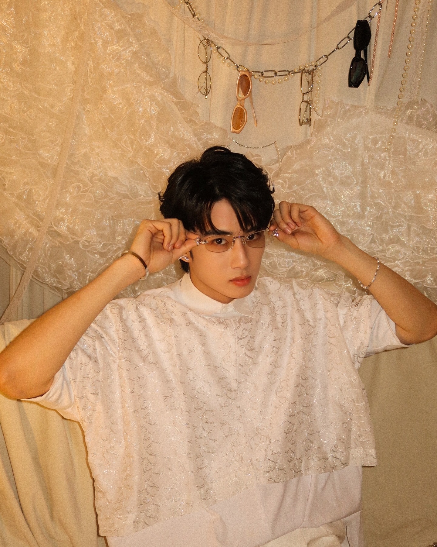 YANG YAN in a white lace top adjusting glasses against a tulle backdrop