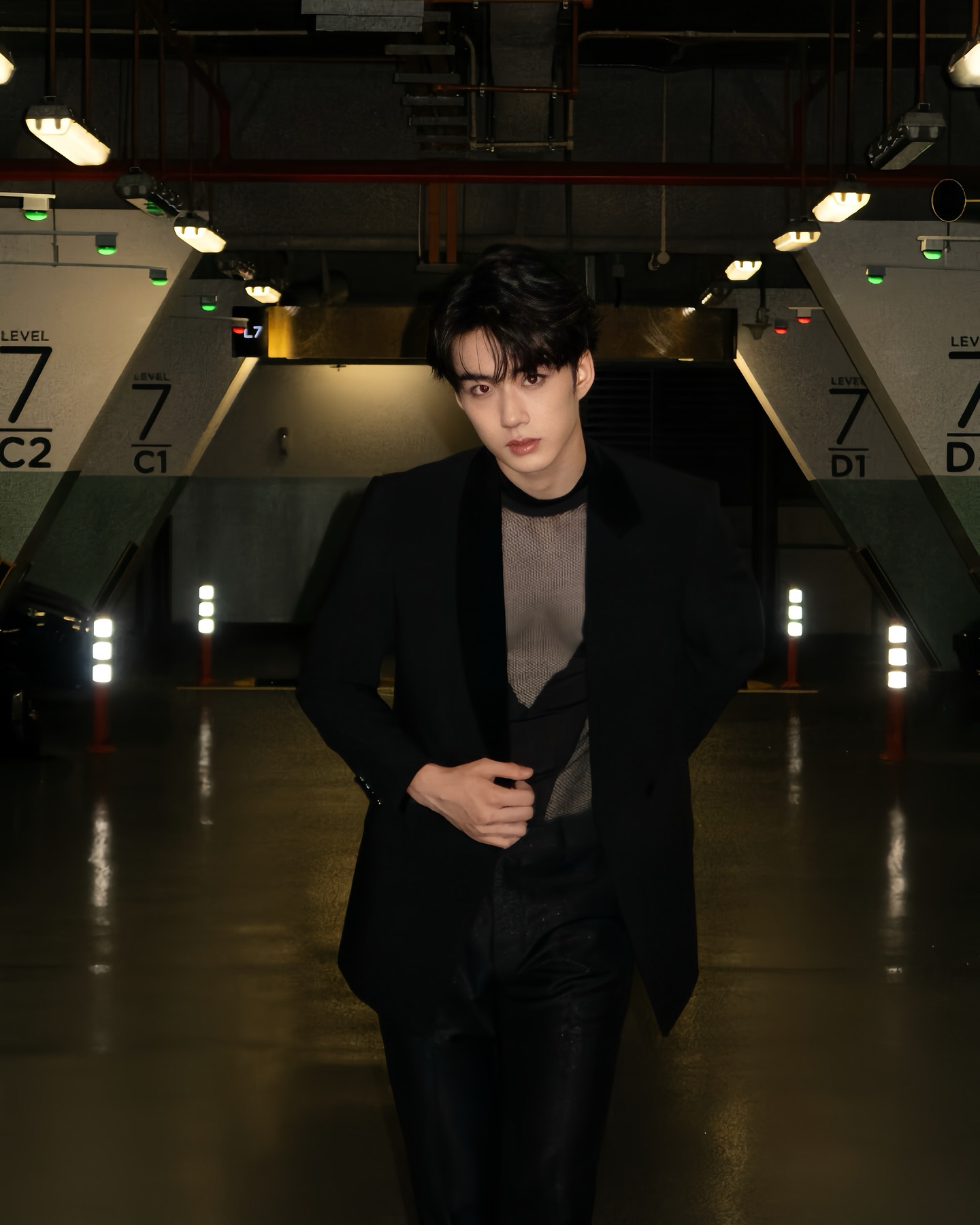 YANG YAN in a black blazer and mesh top in a parking garage