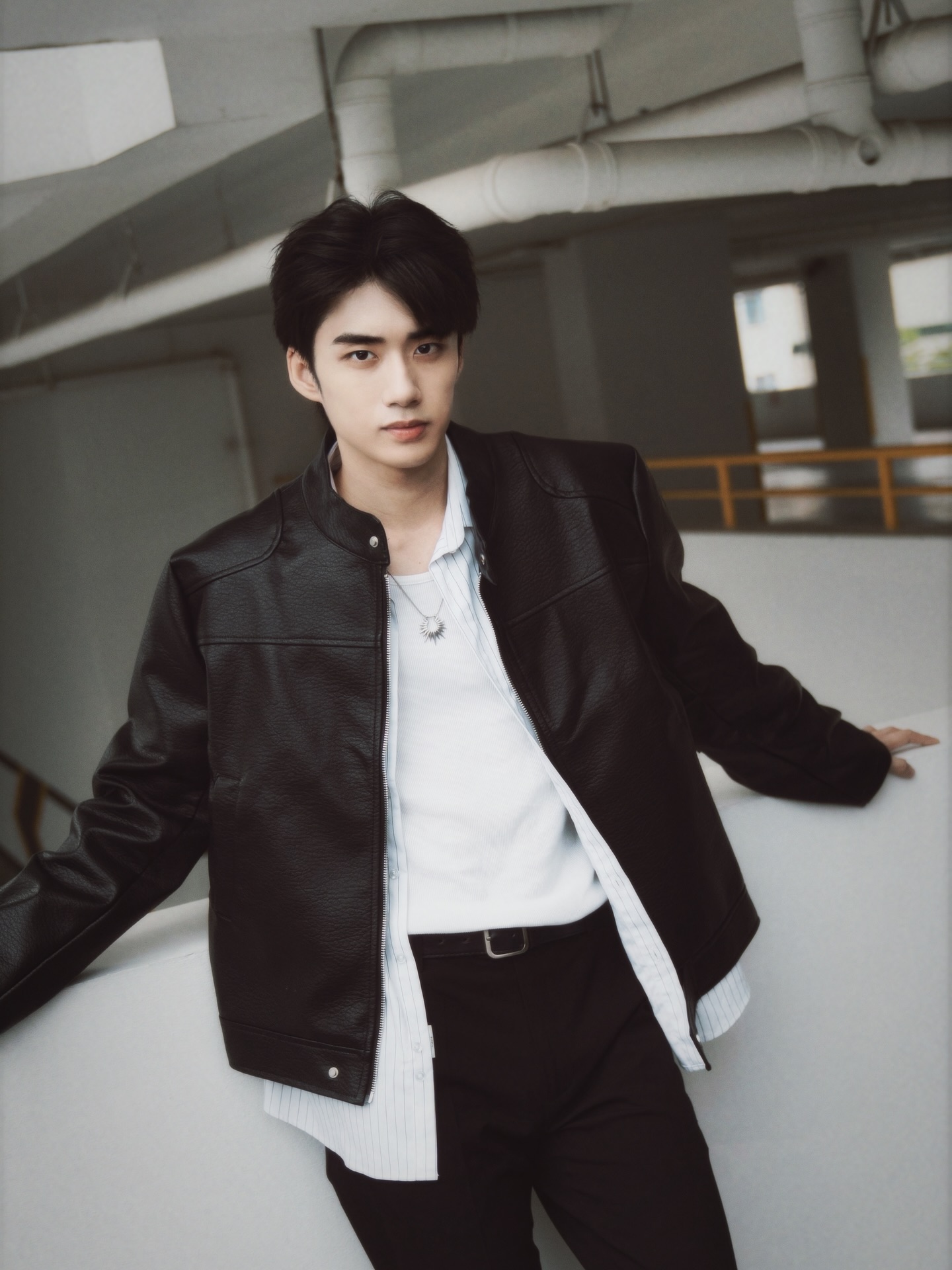 YANG YAN in a black leather jacket leaning on a ledge