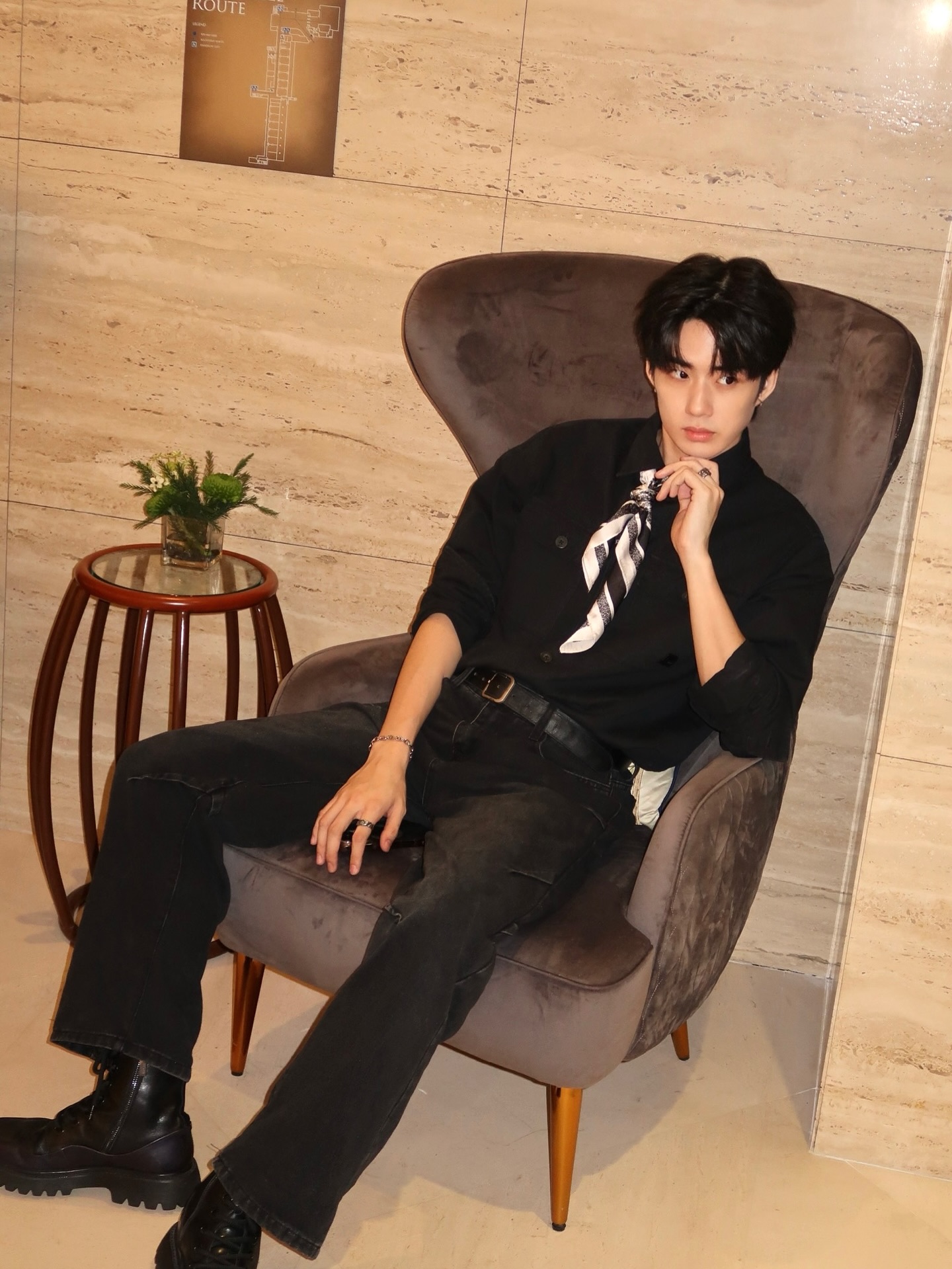 YANG YAN in a black shirt and silk scarf seated in an armchair