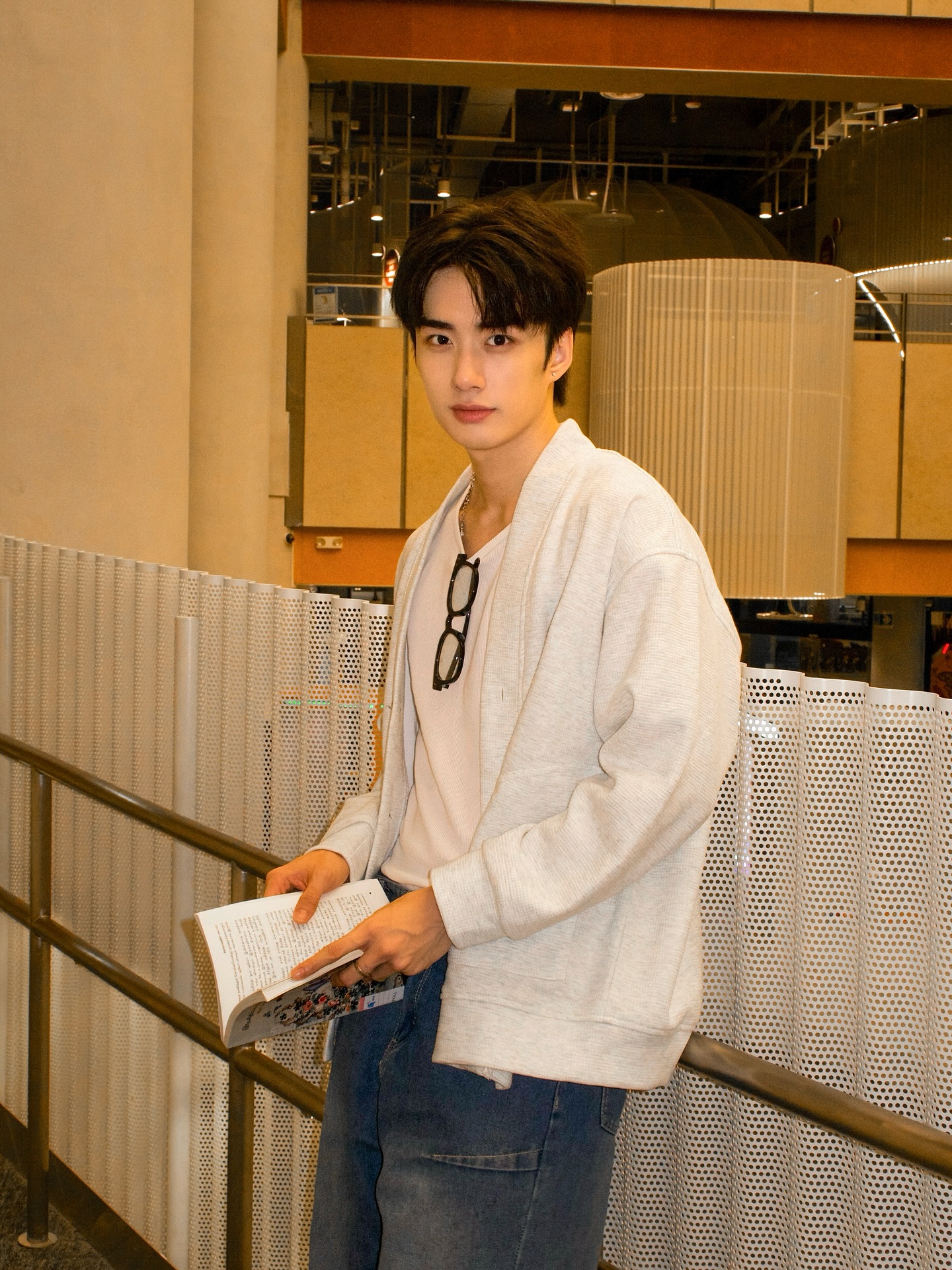 YANG YAN in a white cardigan holding a magazine in a warm-lit interior