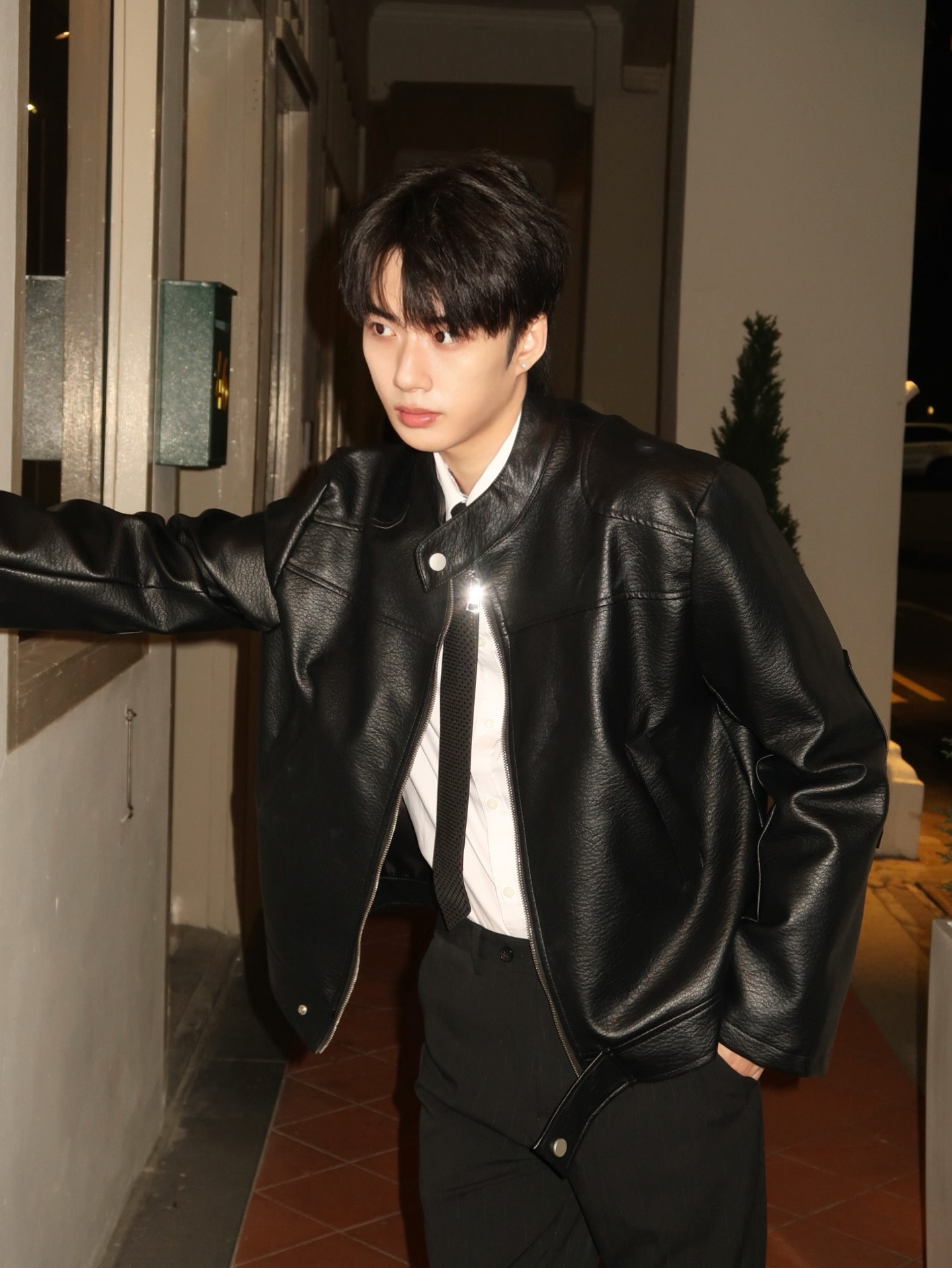 YANG YAN in a black leather jacket and tie in a corridor at night