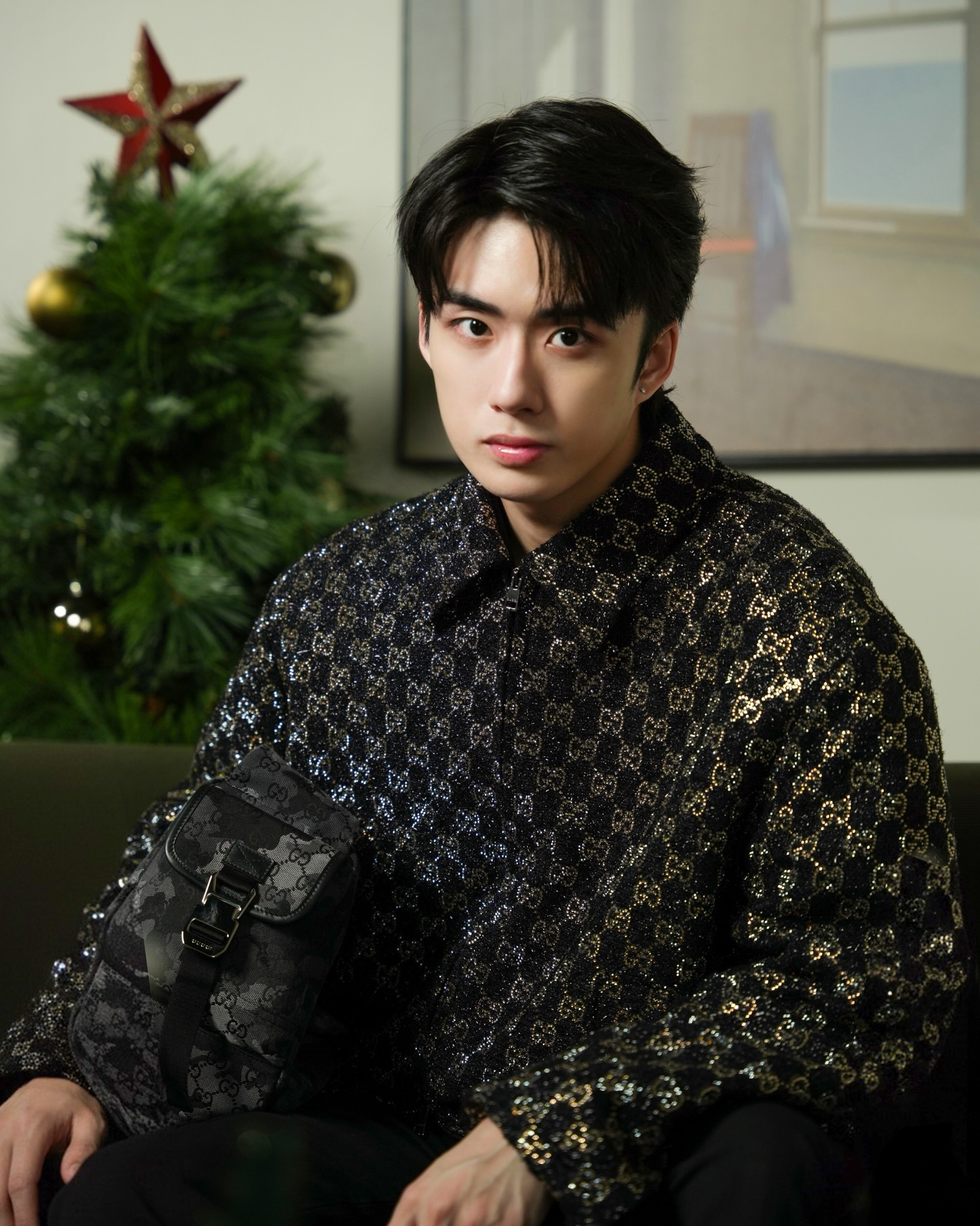 YANG YAN in a sequin monogram shirt with a shoulder bag beside a Christmas tree