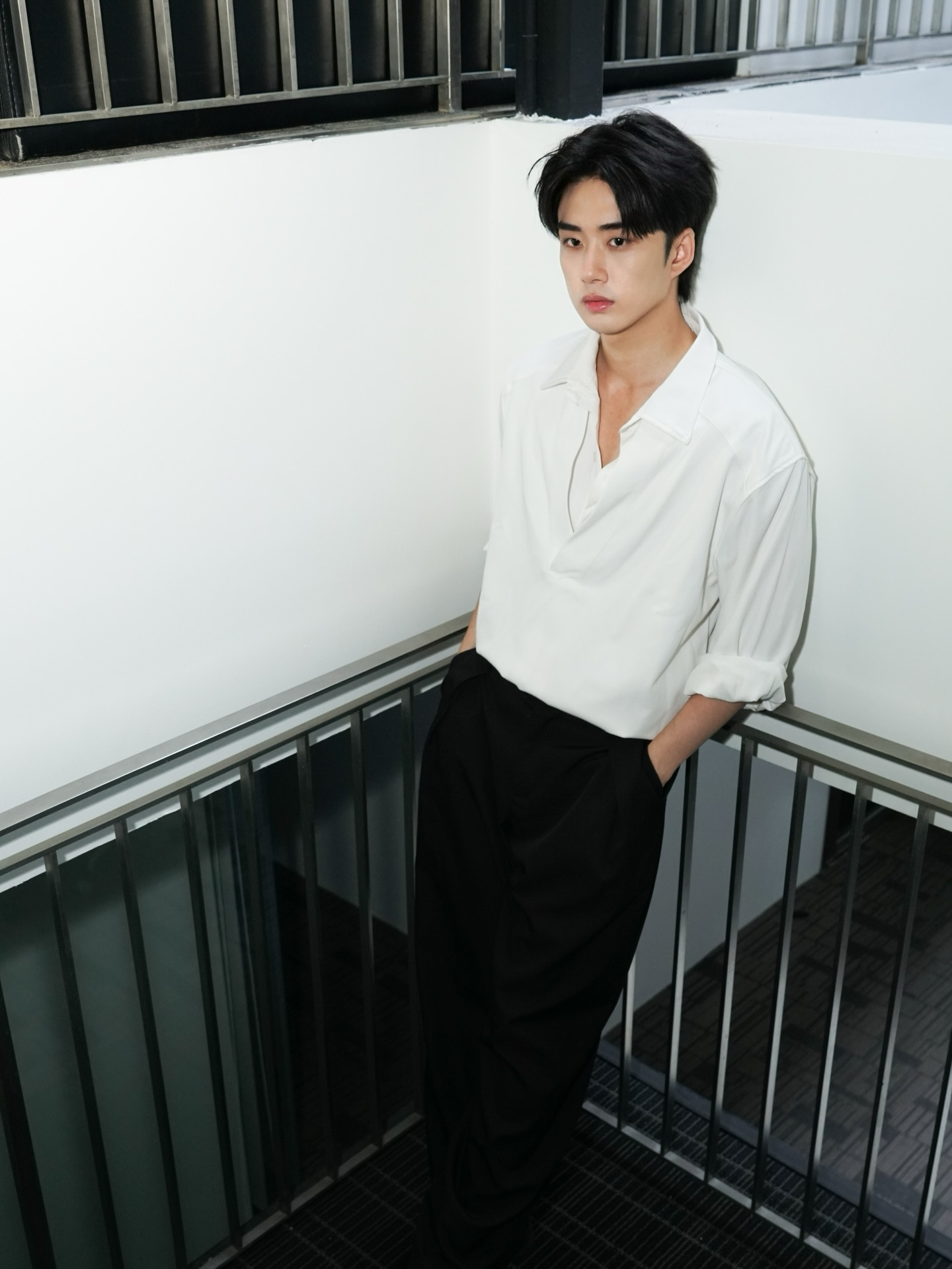 YANG YAN in a white shirt leaning on a walkway railing