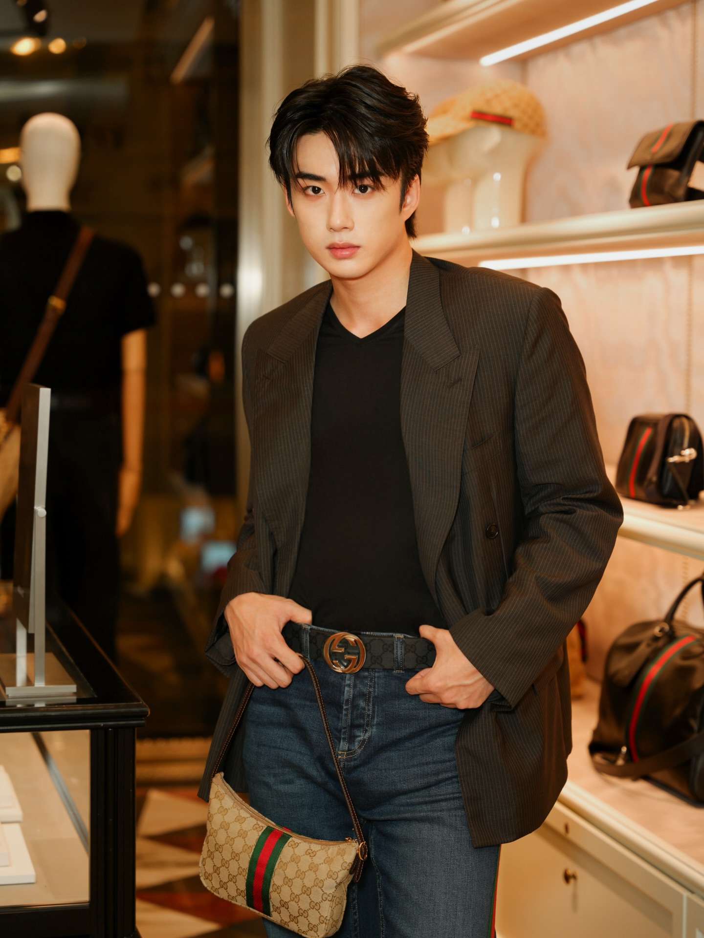 YANG YAN in a pinstripe blazer and jeans with a monogram shoulder bag inside a boutique